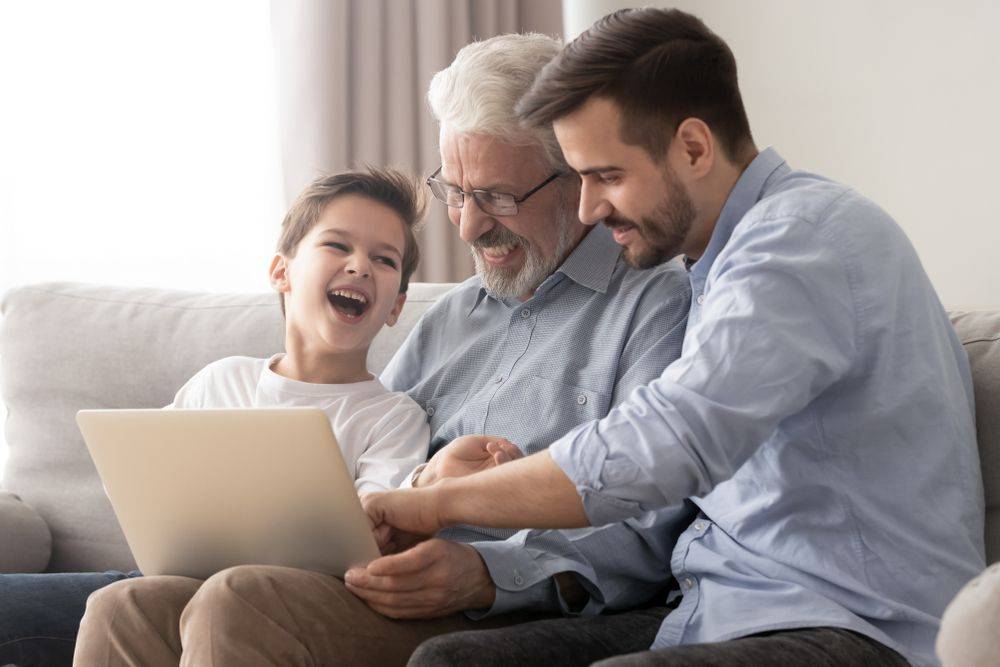 boy, grandpa, and dad laughing at laptop