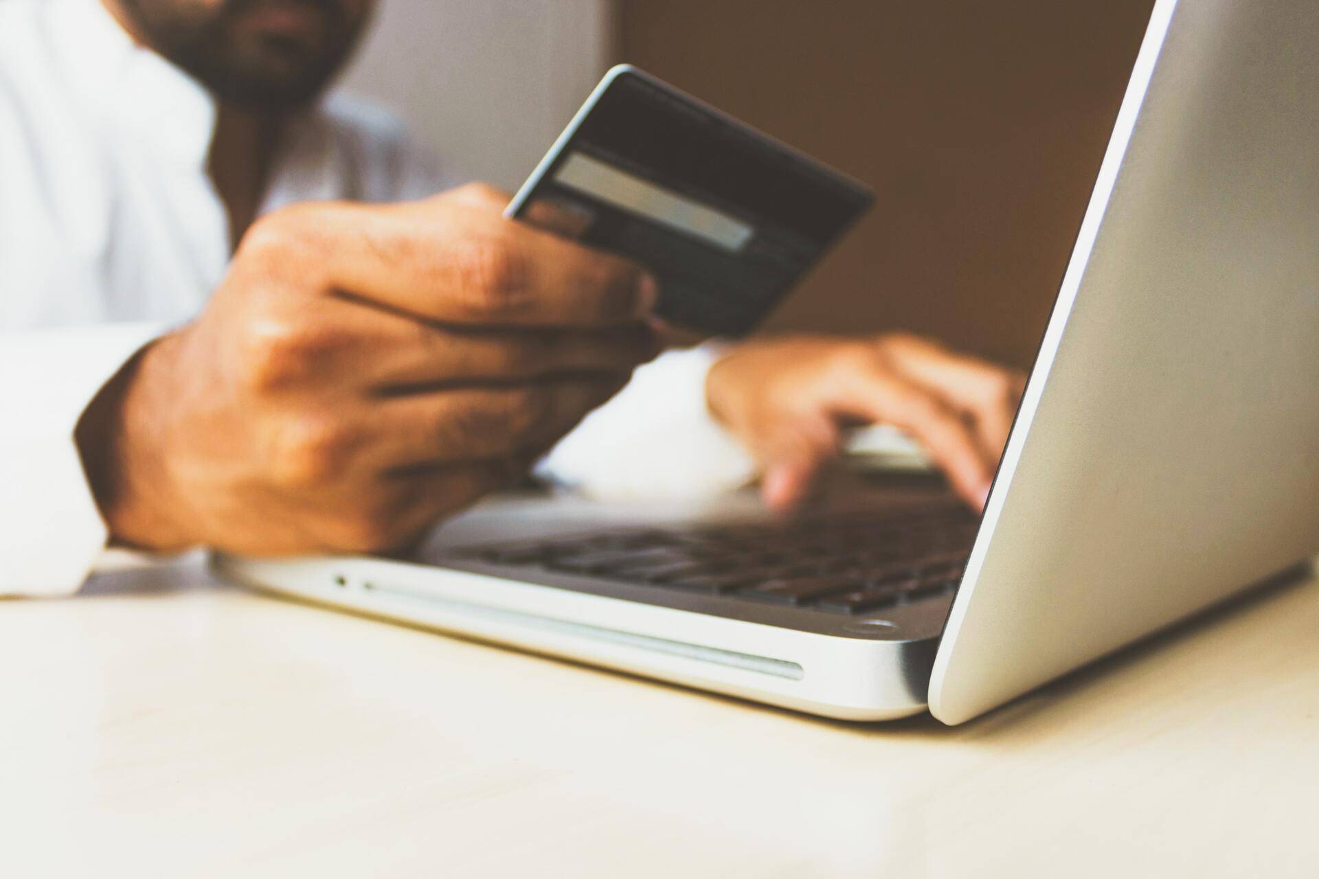 man entering credit card number into laptop