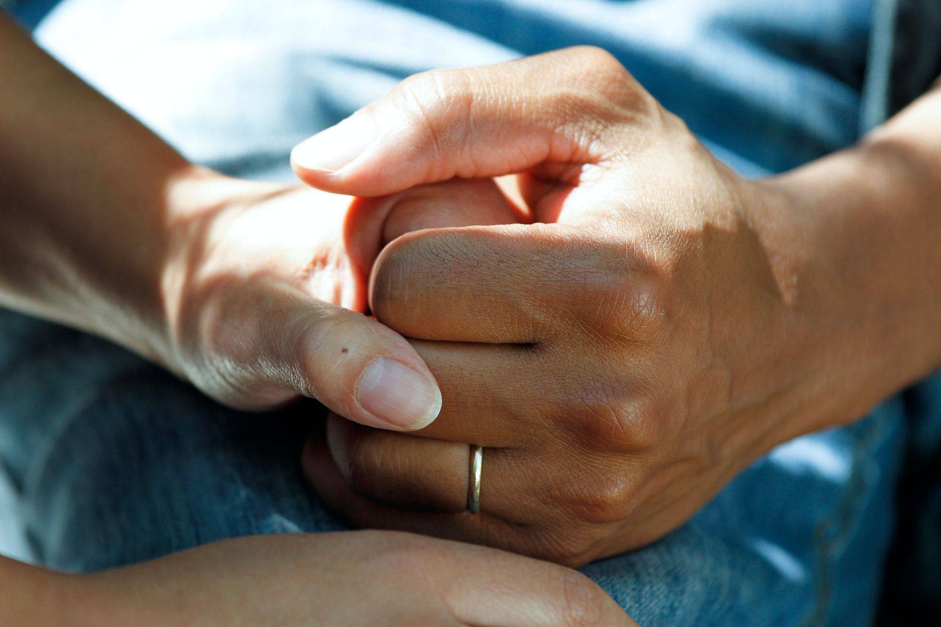 carer clasping hands with cancer patient