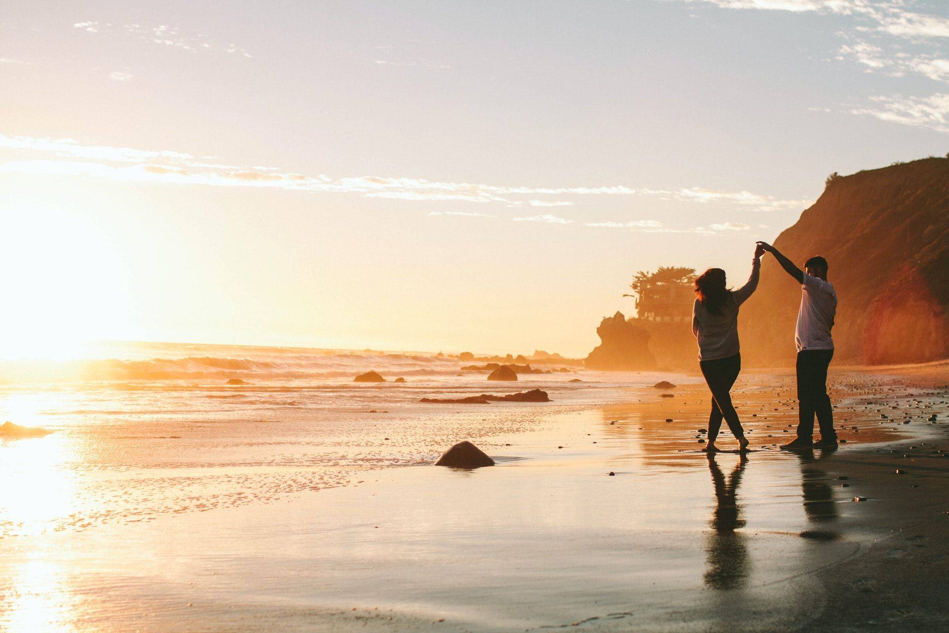 man and woman dancing on the beach at twilight