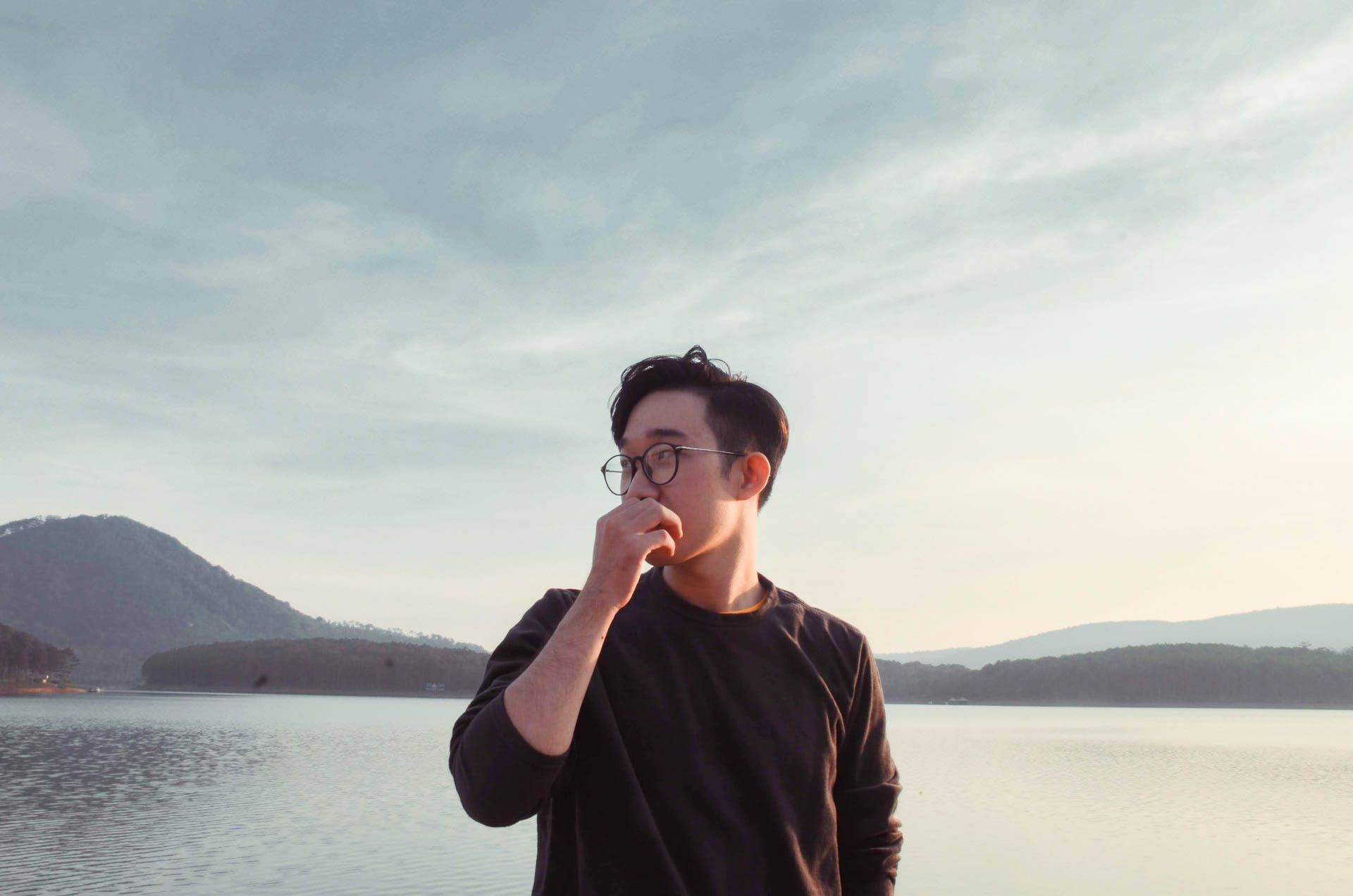 asian man pondering by a lake