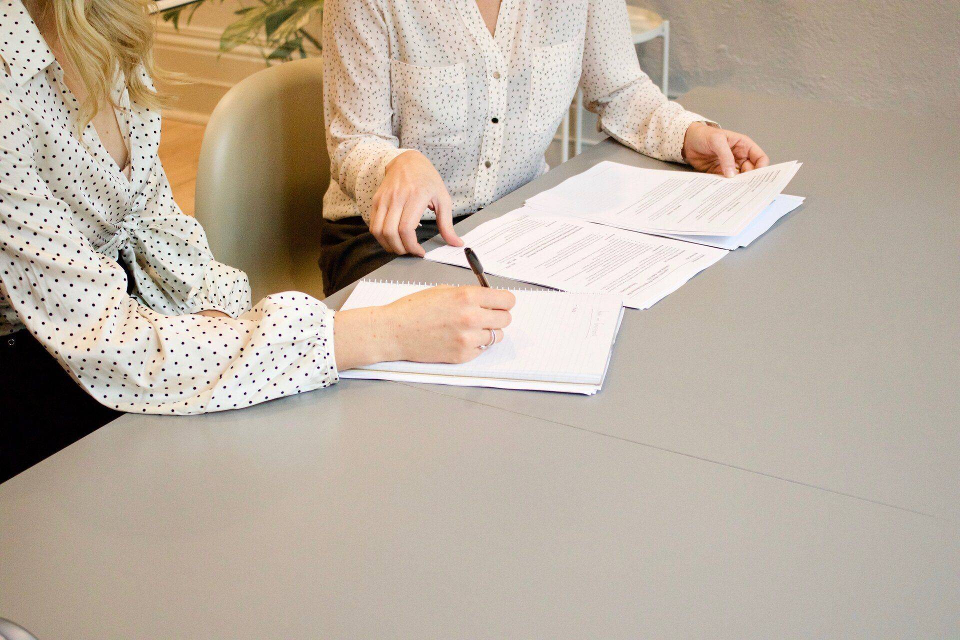 two women signing documents at a table
