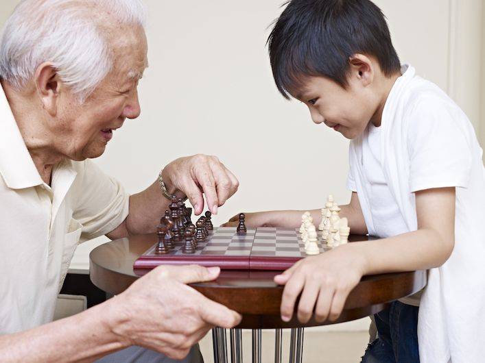 grandfather playing chess with grandson: hk elderly has the world's highest life expectancy
