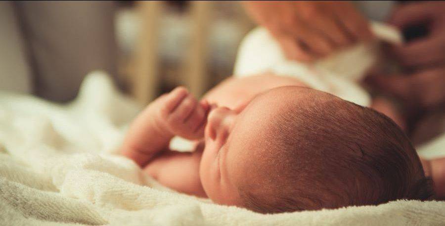 newborn baby getting diaper on