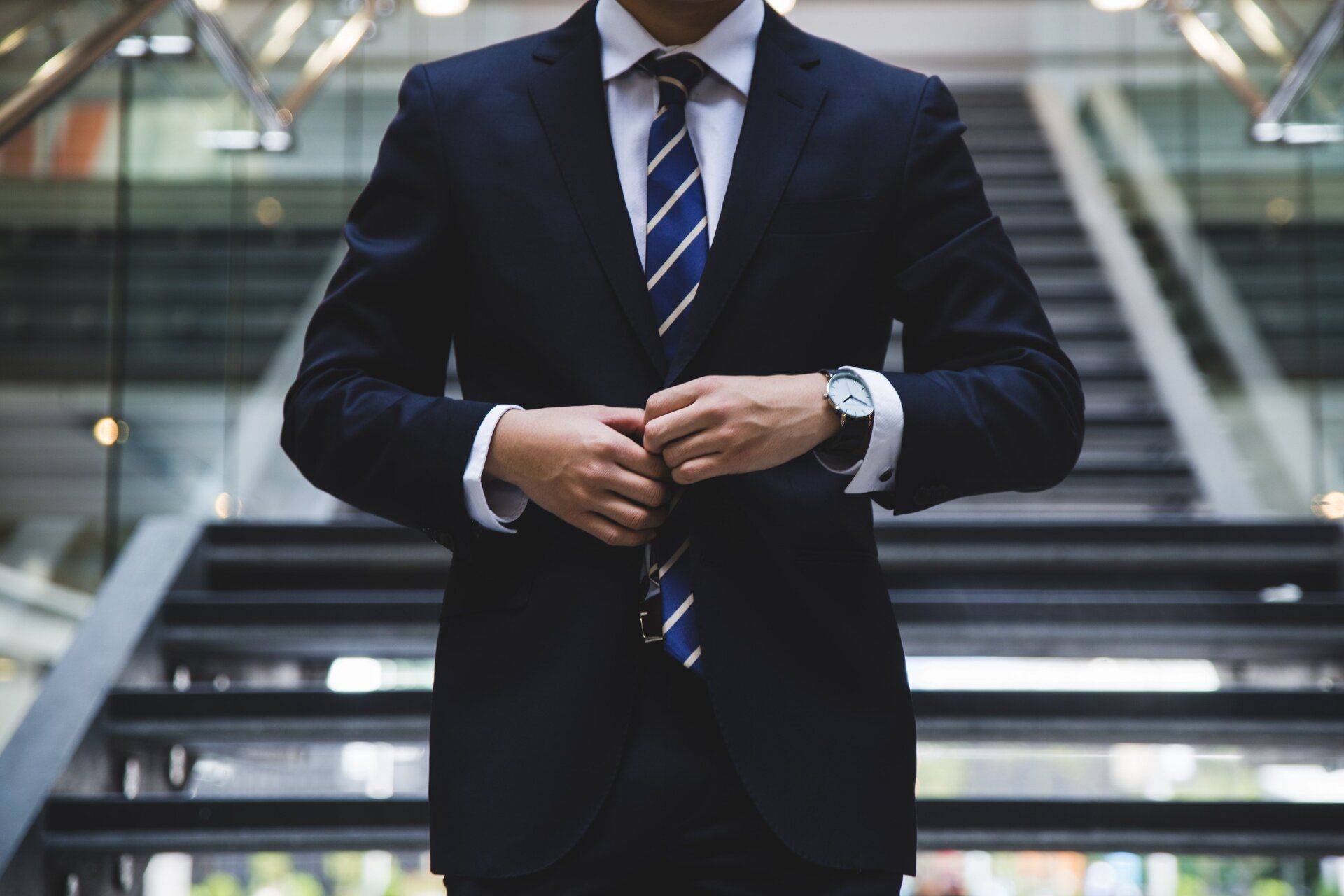 man in suit in front of staircase in office building